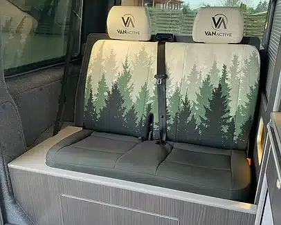 Innenraum mit Sitzbank und Stauraumlösung des VA102 Premium Campers mit Walddesign-Polsterung.