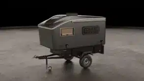 Der Vulpes S Micro-Camper von Pathless Campers auf einem Einachsanhänger in einer Studio-Umgebung