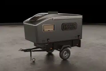 Der Vulpes S Micro-Camper von Pathless Campers auf einem Einachsanhänger in einer Studio-Umgebung