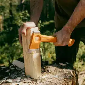 Person verwendet die Fiskars X13 Ultraleichte Wanderaxt, um Holz zu spalten.