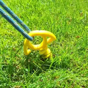 Gelber Schraubanker aus Kunststoff mit Seil, eingeschraubt im Gras
