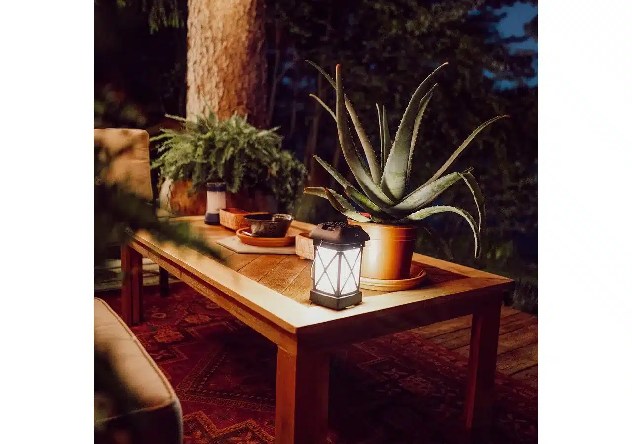 Thermacell MR-9W Terrassenlaterne leuchtet auf einem Holztisch mit Pflanzen bei Dunkelheit