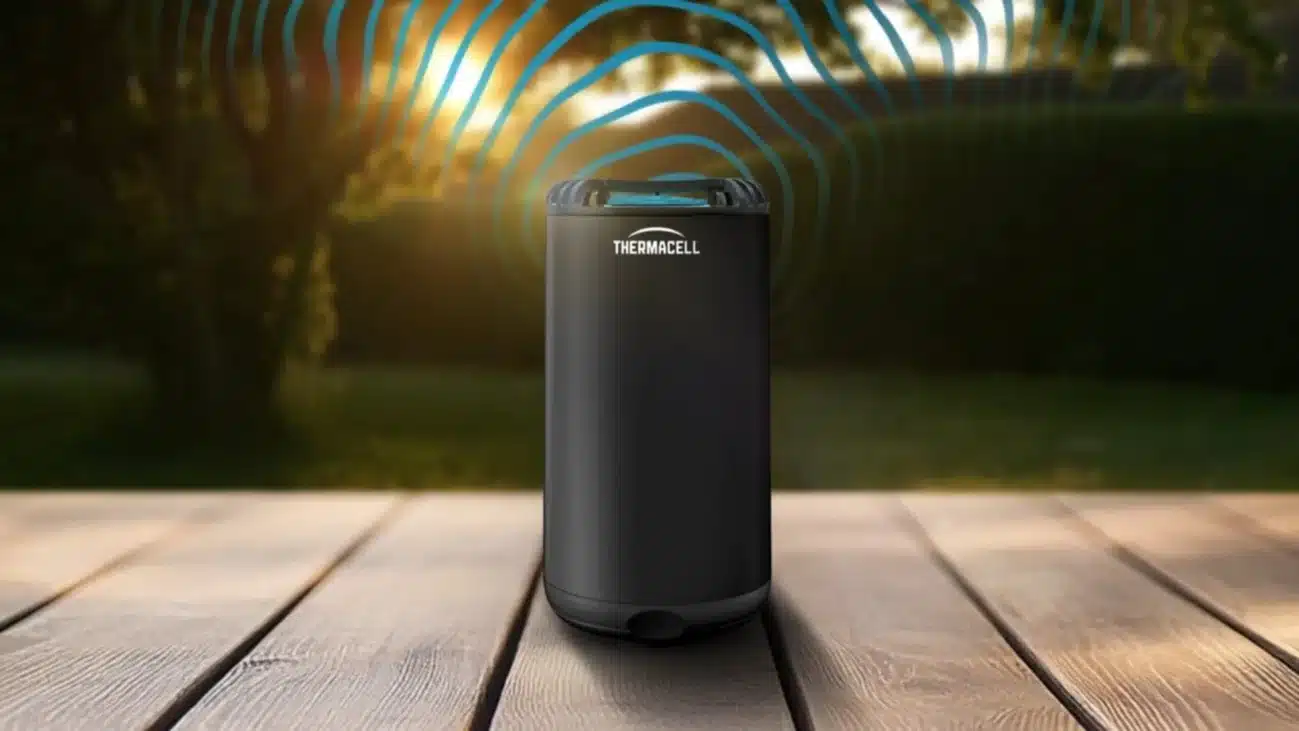 Thermacell Halo Graphit Mückenabwehr-Tischgerät steht auf einem Holztisch im Garten bei Sonnenuntergang.