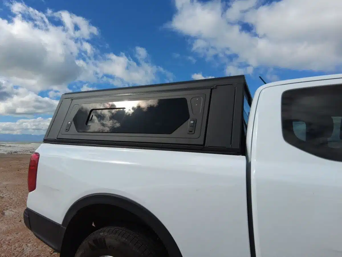 Seitliche Ansicht eines weißen Pickups mit montiertem schwarzen Contour Canopy unter blauem Himmel