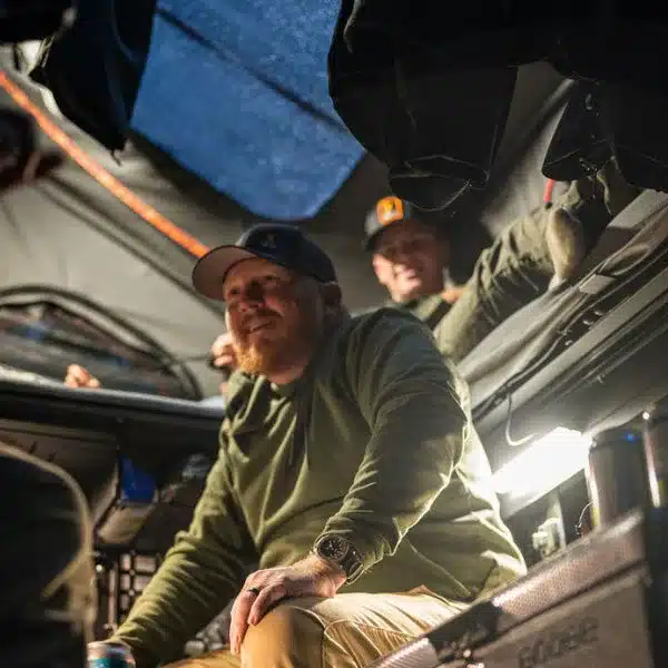 Mehrere Personen sitzen im Innenraum des Alu-Cab ModCAP Family Camper-Aufbaus auf einem Pick-up.
