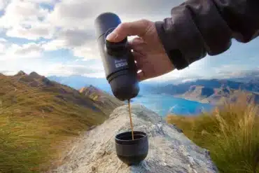 Hand bereitet mit der Wacaco Nanopresso Espresso vor Bergpanorama zu.