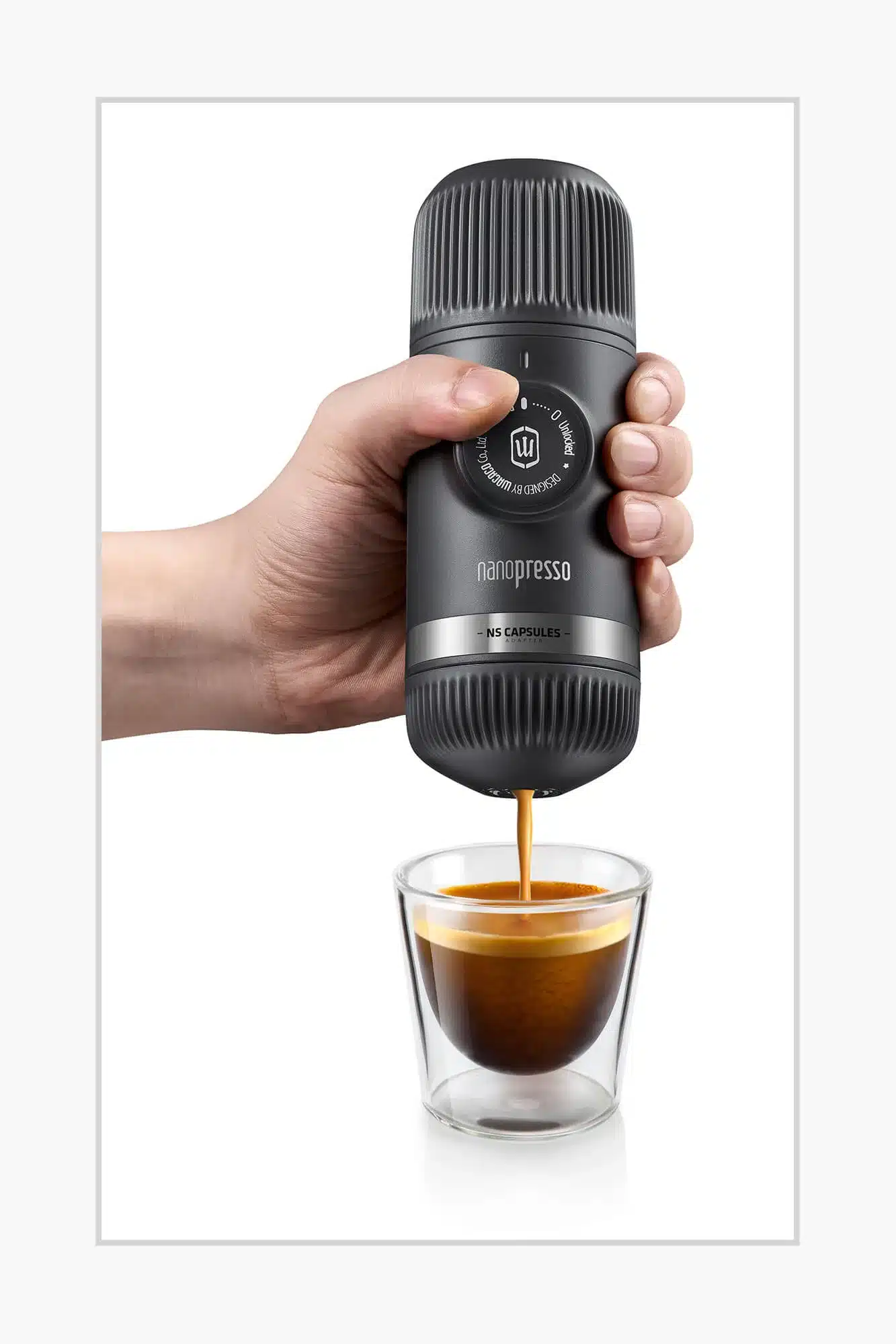 Hand hält die Wacaco Nanopresso in Grau über einem Glas, während frisch gebrühter Espresso aus der Espressomaschine läuft.
