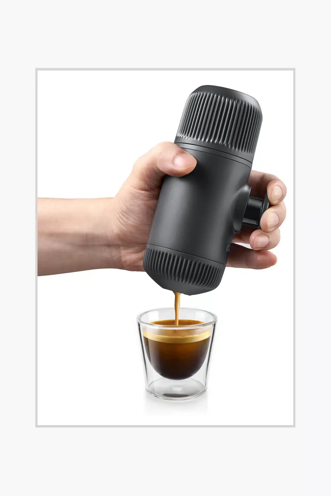 Hand hält eine Wacaco Nanopresso in Grau und brüht frischen Espresso direkt in ein Glas.