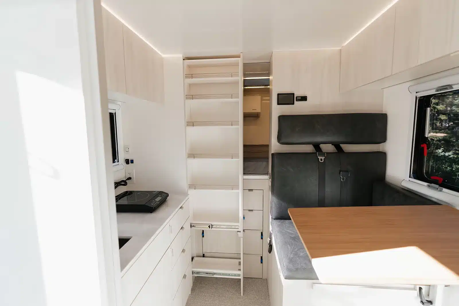 Innenansicht des AEONrv Campers mit Küche, Stauraum, Sitzgruppe und Tisch.