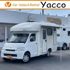 Weißer Asuka Campervan mit Markise auf einem Händlerhof in Japan.