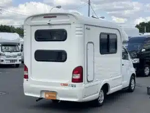 Heckansicht eines kompakten Asuka Campers mit weißen Außenwänden, aufgenommen auf einem Parkplatz.