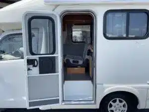 Seitentür eines kompakten Camper Asuka, Blick ins Innere, mit Sitz- und Wohnbereich