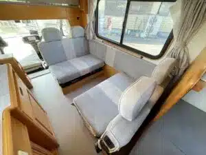 Innenansicht des Asuka Campervans mit Sitzgelegenheiten und großen Fenstern.