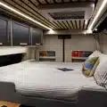 Blick auf das quer eingebaute Doppelbett mit Memory-Foam-Matratze und umliegenden Staufächern im Beyond2c Kastenwagen.