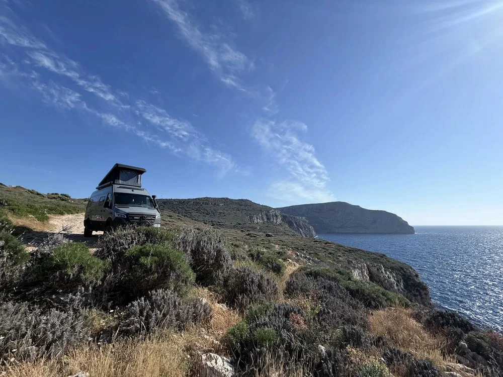 Mercedes Sprinter mit Campany-Aufstelldach vor Küstenlandschaft mit Meer und Felsen