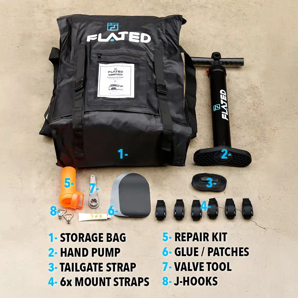 Zubehör des FLATED Air-Topper MR60 wie Tasche, Handpumpe, Gurte und Reparaturset auf dem Boden angeordnet.