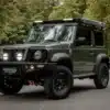 Full Metal Jimny als robuster Offroad-Umbau vor Waldkulisse, bereit für Abenteuerreisen und Vanlife.