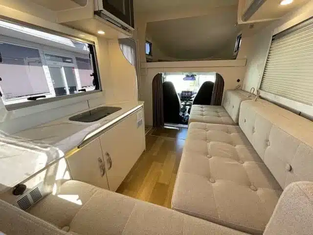 Innenansicht des JPSTAR Happy1+ Micro-Campers mit Sitzbank, Küchenzeile und Blick auf den Fahrerbereich