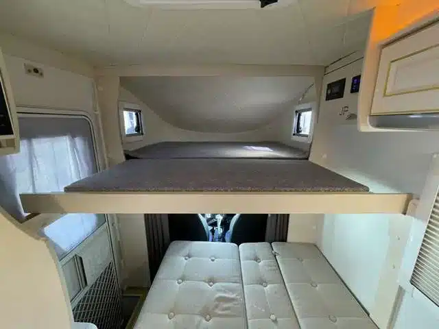 Innenraum des JPSTAR Happy1+ mit Alkovenbett und Sitzbank, kompakter Schlafbereich im Camper