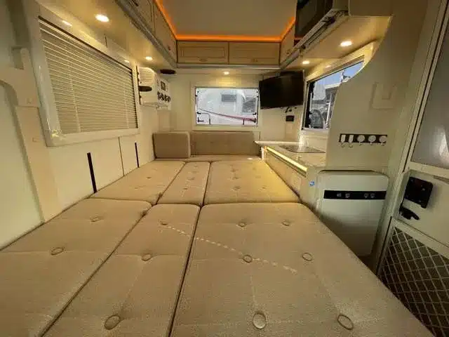 Innenansicht des JPSTAR Happy1+ Micro-Campers mit aufgebautem Bett, Stauraum, TV und Küchenzeile.