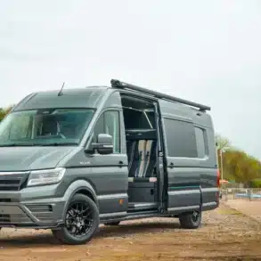 MAN TGE 180 XLWB Race Cruiser Prestige Package als Campervan mit geöffneter Schiebetür auf einem Stellplatz.