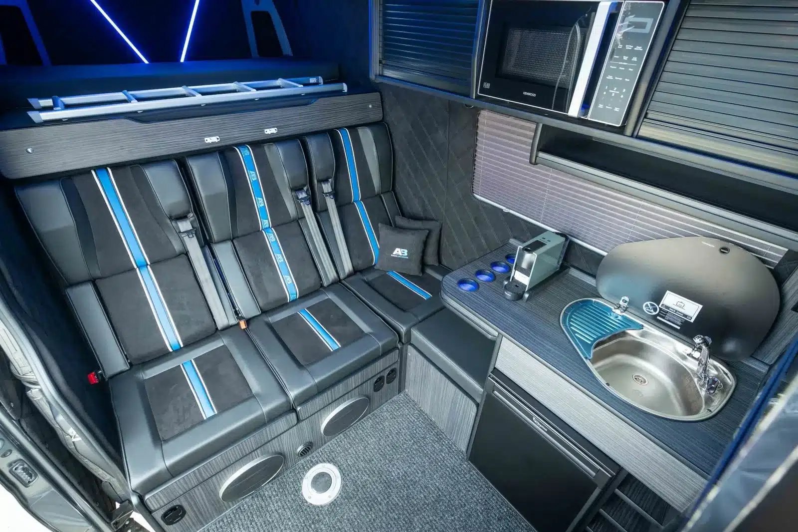 Innenraum des Mercedes Sprinter 319 V6 Race-Van mit Sitzbank, Küche, Kühlschrank und Mikrowelle