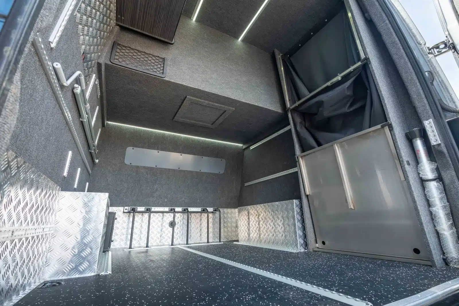 Heckgarage im Mercedes Sprinter 319 V6 von AB Race Cruisers mit Aluminium-Verkleidung und großem Stauraum.