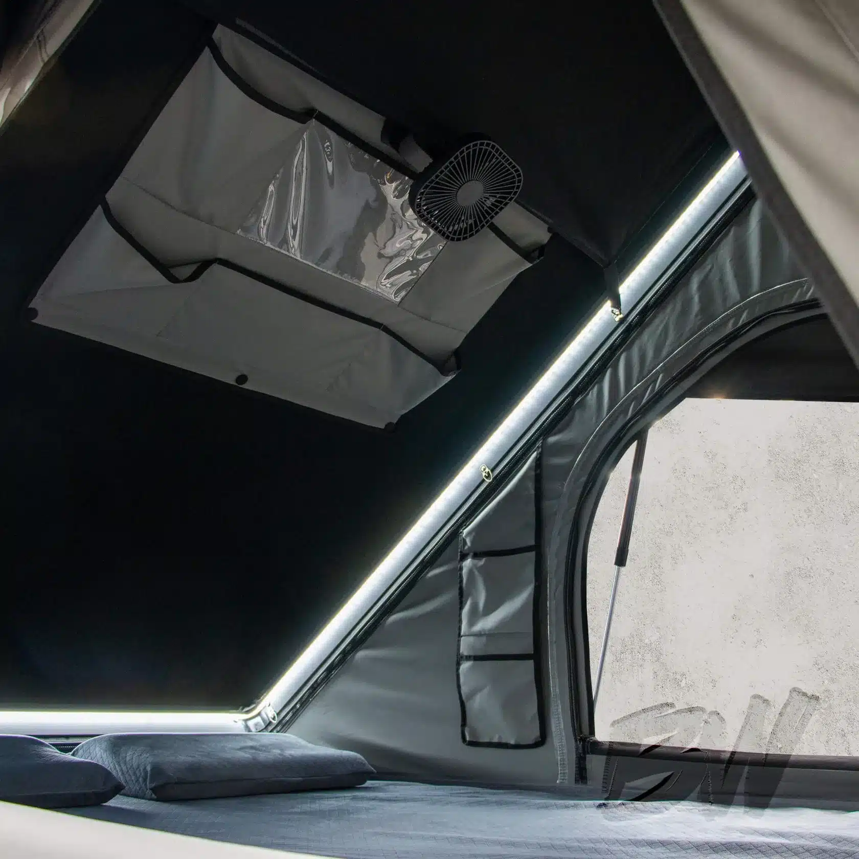 Innenansicht des Nomad Dachzelts mit LED-Lichtleiste, Staufächern und Ventilator.