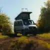 Kastenwagen Sportive mit Aufstelldach auf einem Feldweg, umgeben von Bäumen