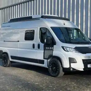 Rocket Base Campervan auf Peugeot-Boxer-Basis in weißer Farbe, seitliche Ansicht vor einer Halle.