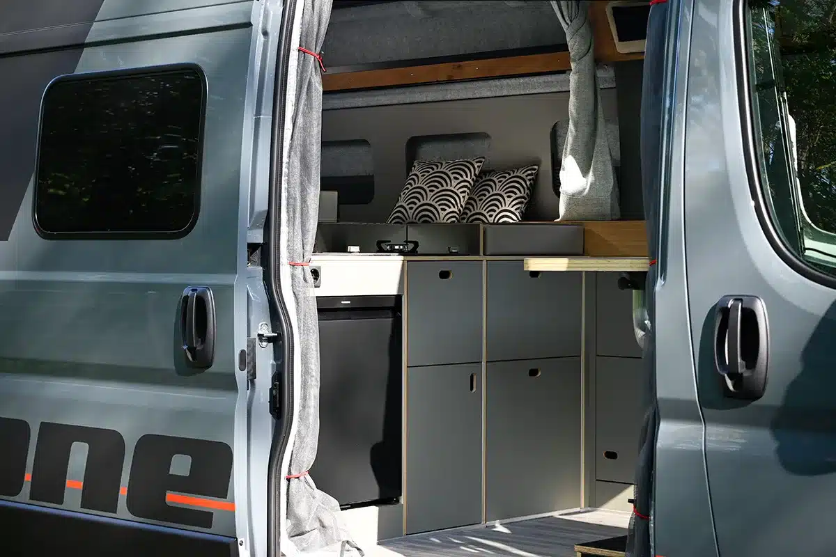 Innenansicht eines Campervans Rocket One L 2.4 P mit Küche, Stauraum und Bettkissen