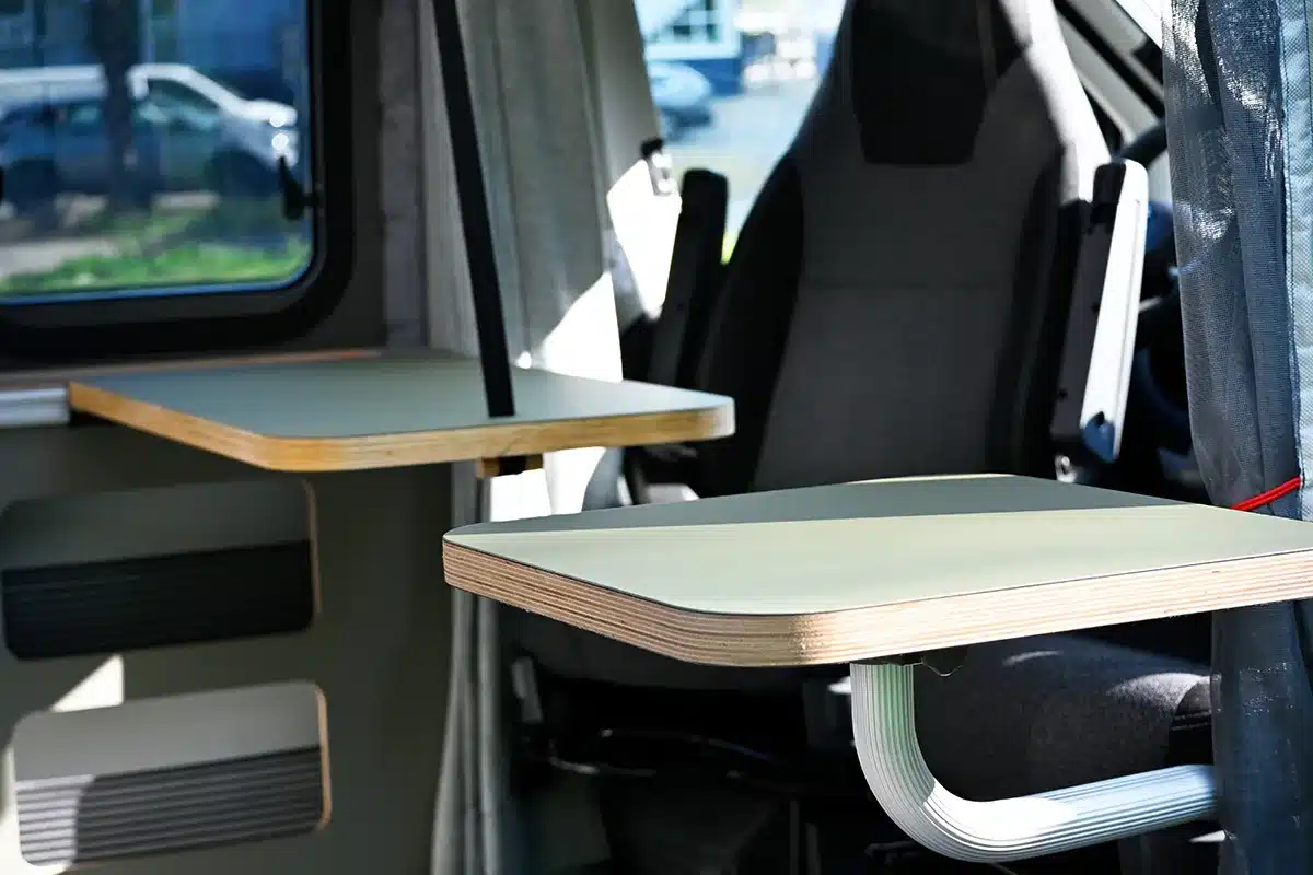 Innenansicht des Campervans Rocket One L 2.4 P mit zwei Klapptischen und Fahrersitz