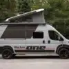 ROCKET ONE M Campervan mit geöffnetem Aufstelldach im Wald, Seitenansicht