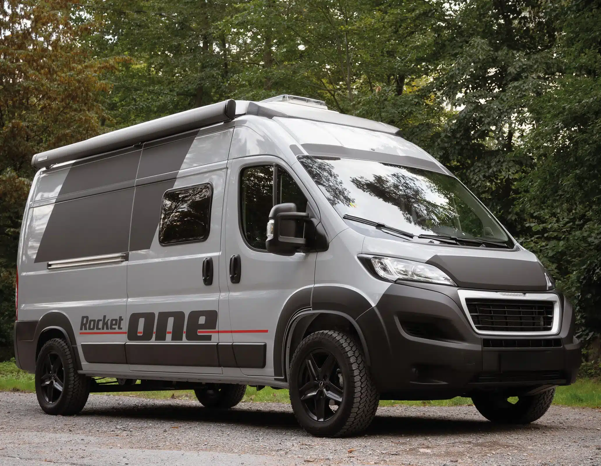 Rocket One M Campervan von außen, silbergrau, mit Markise, im Grünen geparkt