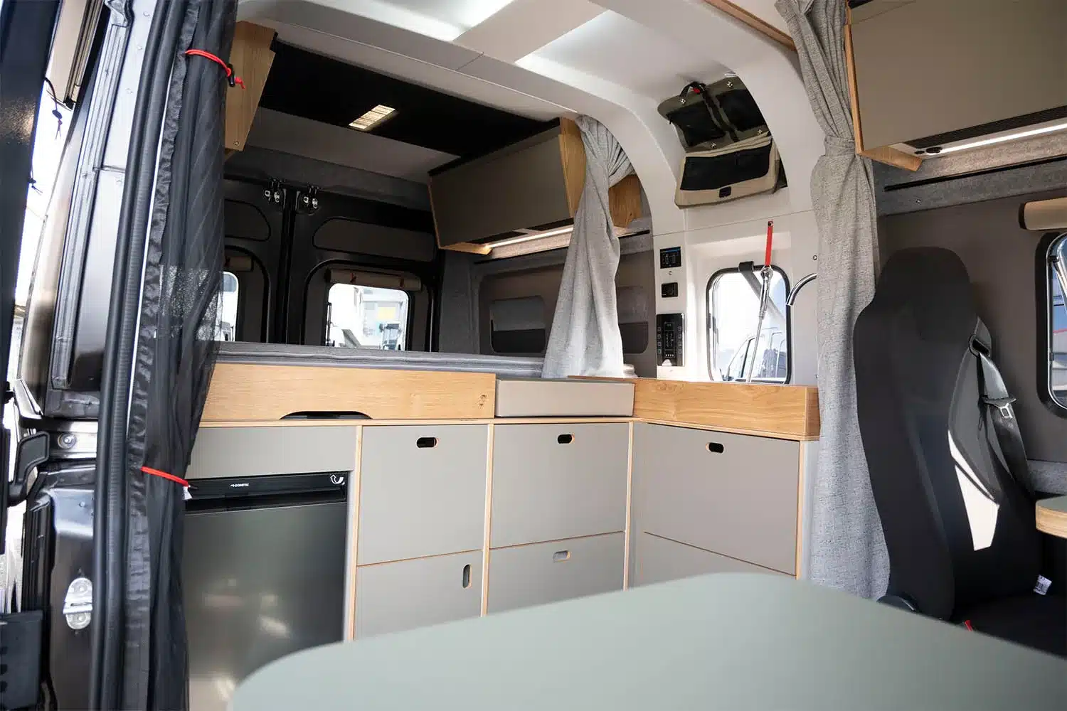 Das Bild zeigt den Innenraum des Campingfahrzeugs ROCKET ONE M mit Küche, Oberschränken und Sitzgelegenheit.