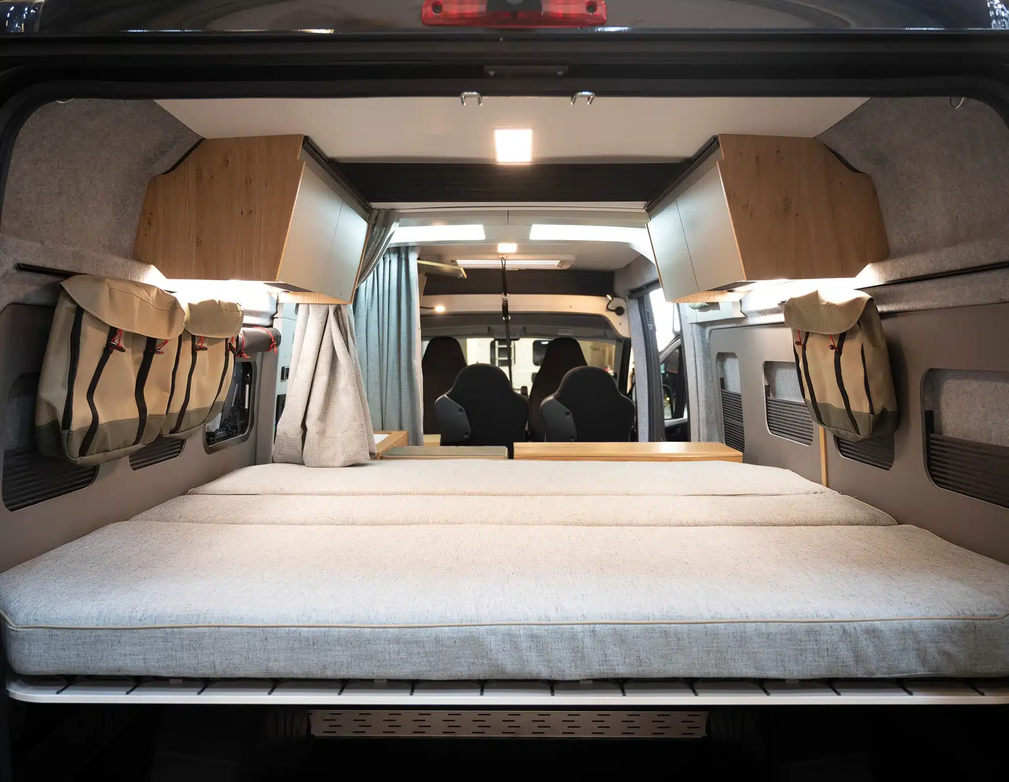 Heckbett mit Komfort-Tellerfedern im Rocket One XL Kastenwagen, Blick nach vorn, mit Staufächern und Hängeschränken.
