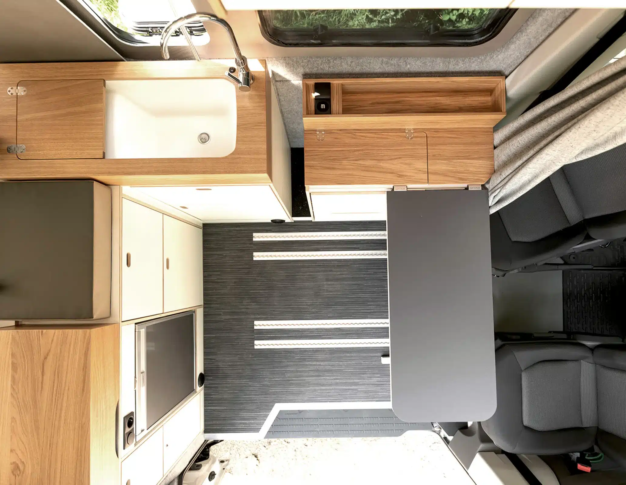 Vogelperspektive auf den Innenraum eines Rocket TGE mit Sideboard, Küchenmodul und ausklappbarem Tisch.