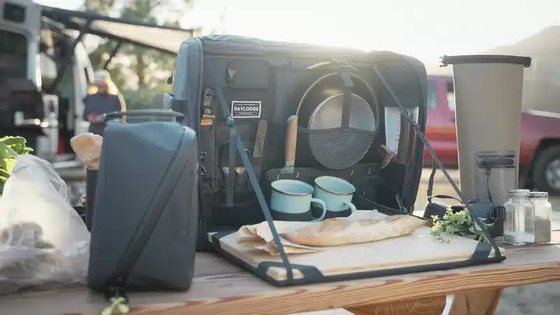Workspace Mobile Camp Kitchen mit Zubehör und Utensilien auf Campingtisch vor Van.