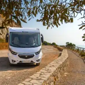 Frontansicht des Benimar Amphitryon A967 Wohnmobils auf einem Parkplatz an einer Küstenstraße mit Blick aufs Meer.