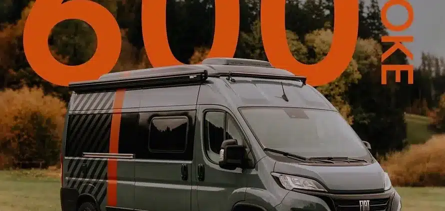 Algovia Evoke 600 Campervan seitlich vor Bäumen, großflächiger oranger 600-Schriftzug im Hintergrund