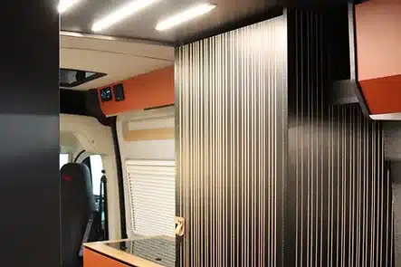 Detailaufnahme vom Innenraum des Algovia Escape mit Eichelamellen als Raumtrenner und moderner Beleuchtung.