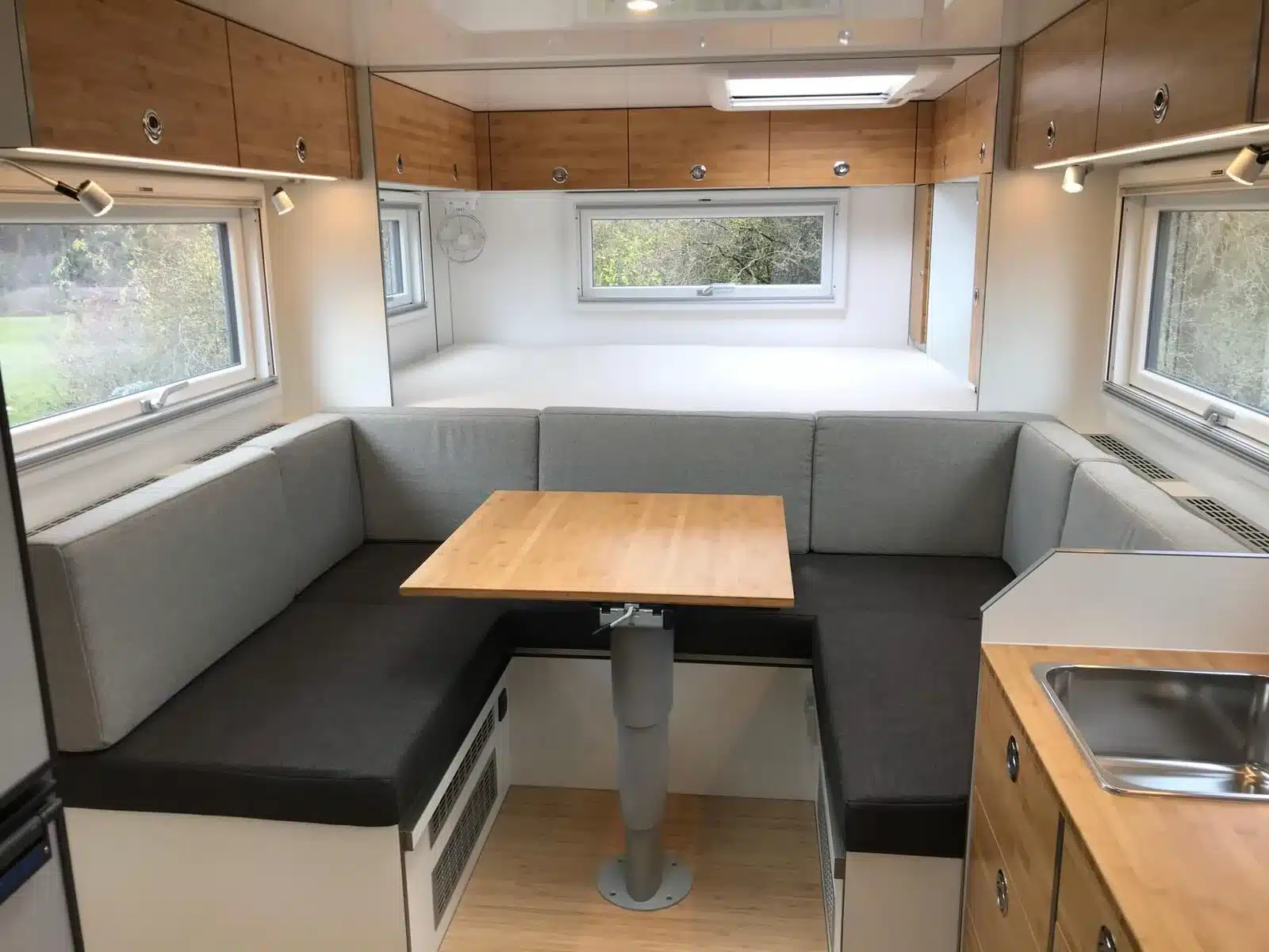 Innenraum des Arocs 4x4 Expeditionsmobils mit Sitzdinette, Bett, Küchenzeile und Stauraum