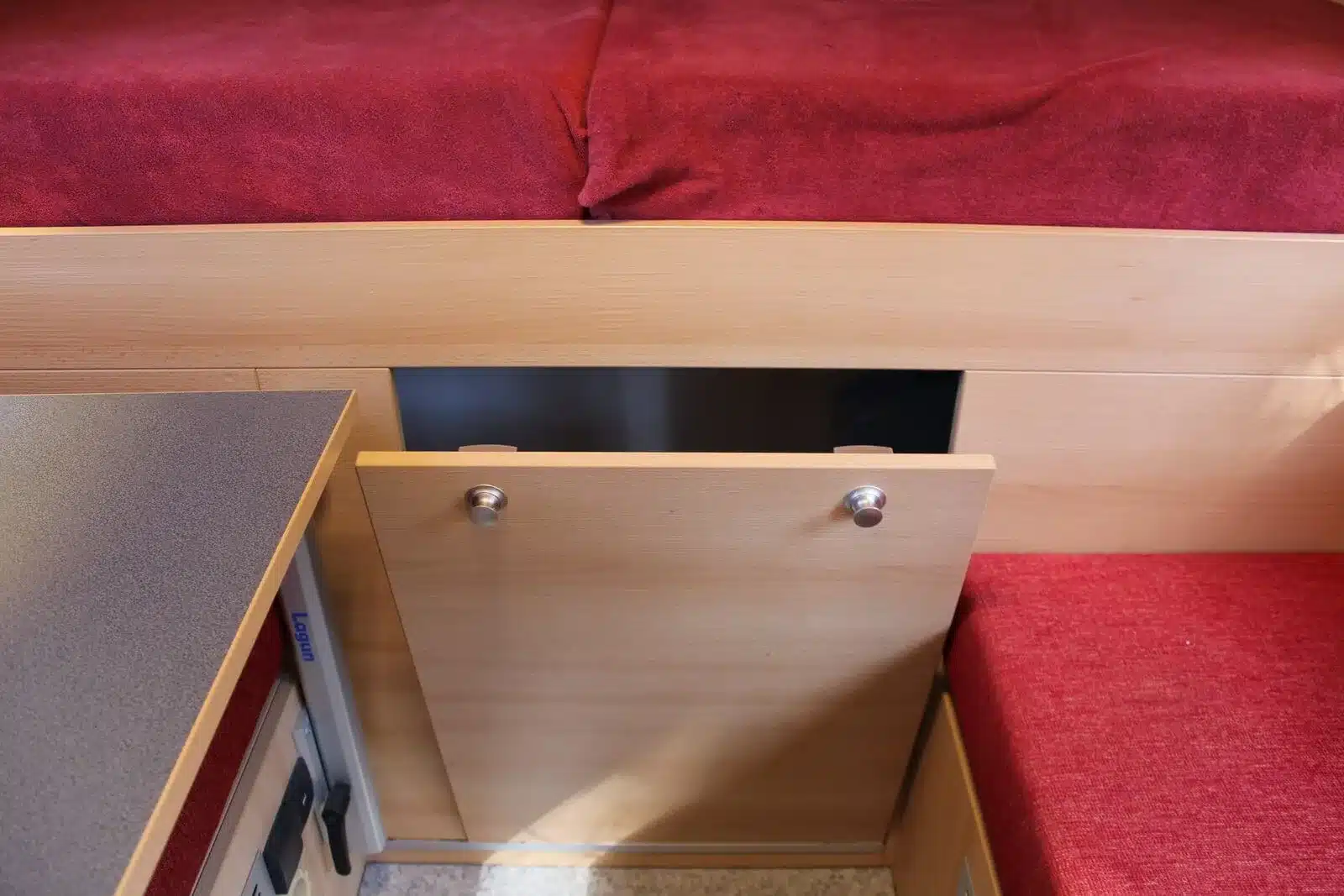 Innenraum des Autark Hilux Extra Cab 2018 mit Holzschrank, Schublade und roten Sitzpolstern