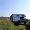 Der Woelcke Autark Hilux, ein Offroad-Reisemobil mit Alkoven, abgestellt in freier Natur auf einer Wiese