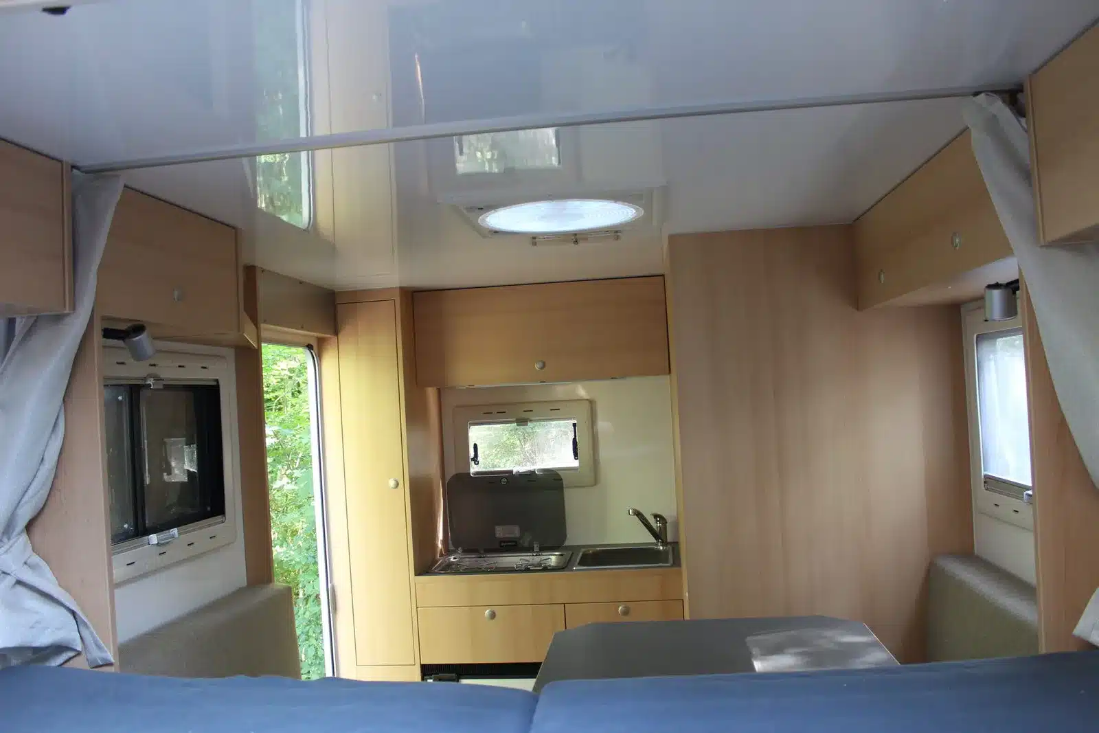 Blick in den Innenraum eines Woelcke Autark Hilux Campers mit Alkovenbett, Küchenzeile und Stauraum