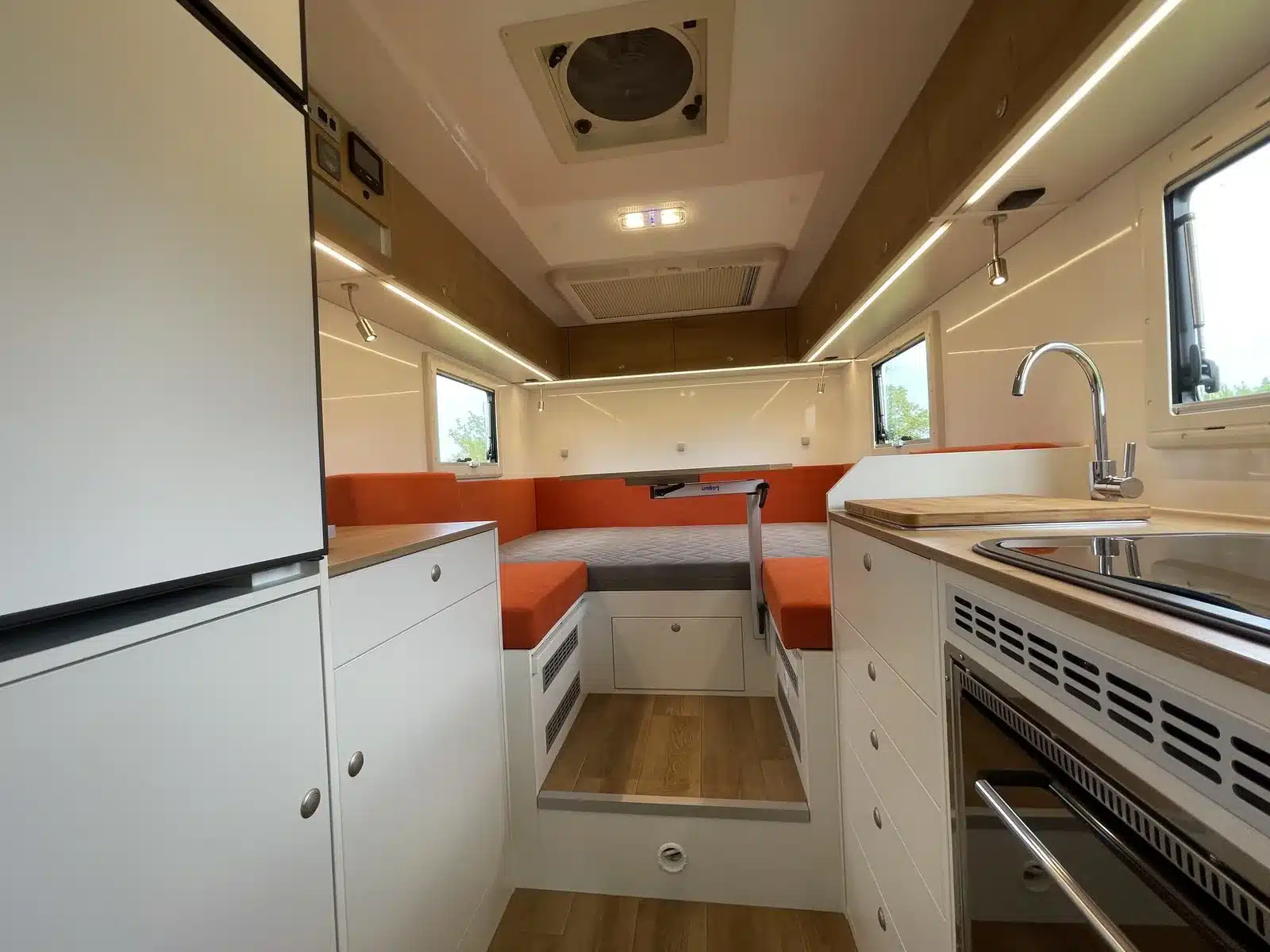 Blick in den Innenraum des Autark Runner R9 2023 mit Küche, Waschbecken, Backofen und Sitz-/Schlafbereich