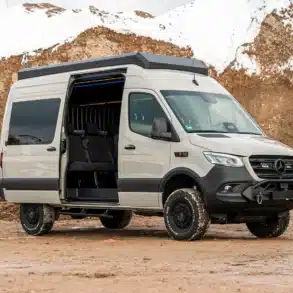 VANME BEDROCK 4x4-Campervan auf Sprinter-Basis mit geöffnetem Schiebetür, Offroad-Umbau und Dachaufbau auf schlammigem Untergrund