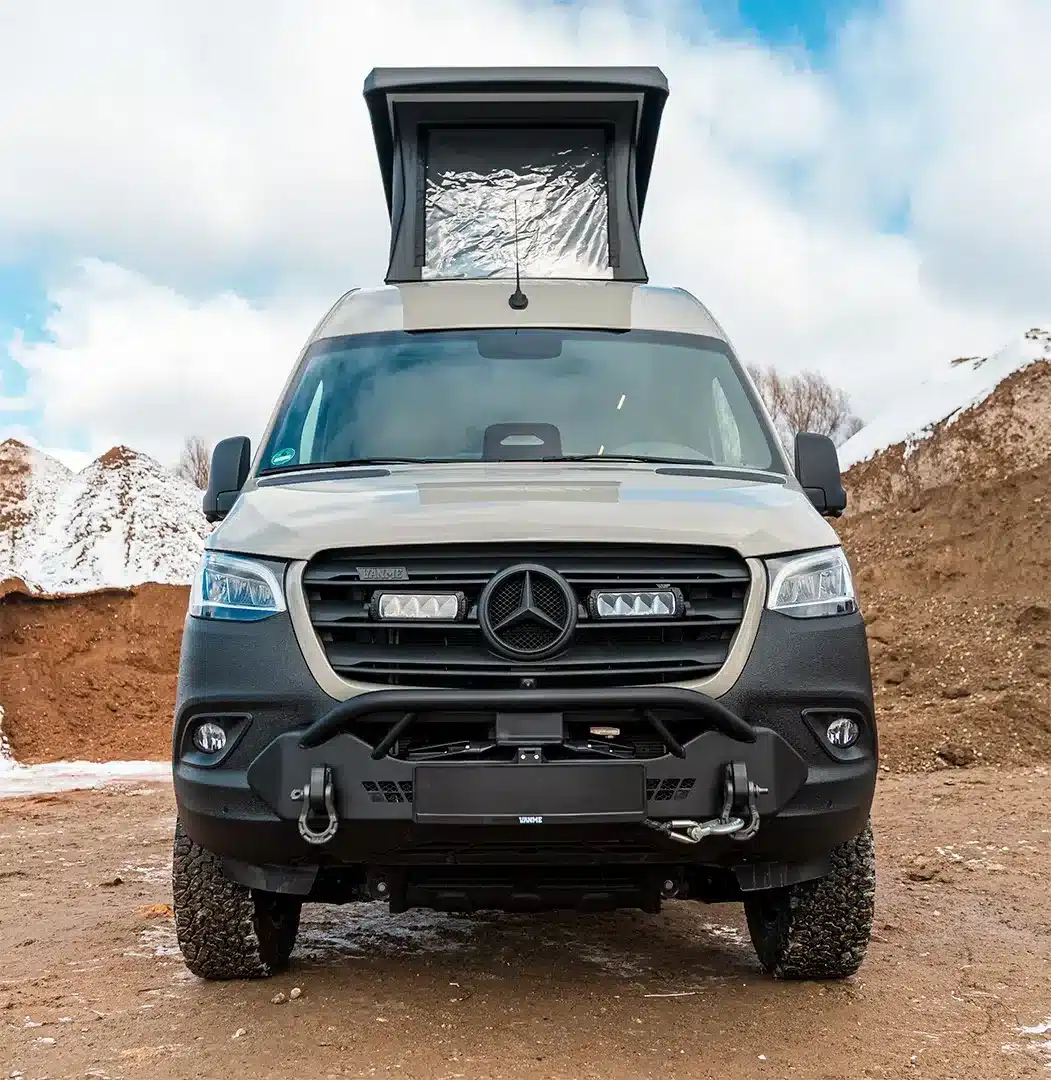 Der VANME BEDROCK 4x4 Camper auf Mercedes Sprinter Basis mit geöffnetem Aufstelldach und Offroad-Ausstattung, fotografiert in einer Outdoor-Umgebung.