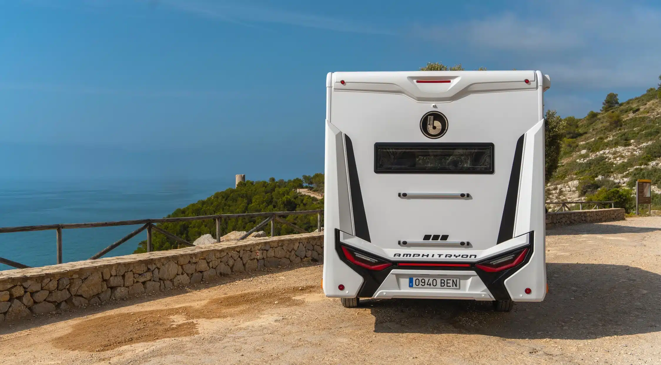 Heckansicht des Benimar Amphitryon A940 Reisemobils vor einer Küstenlandschaft.