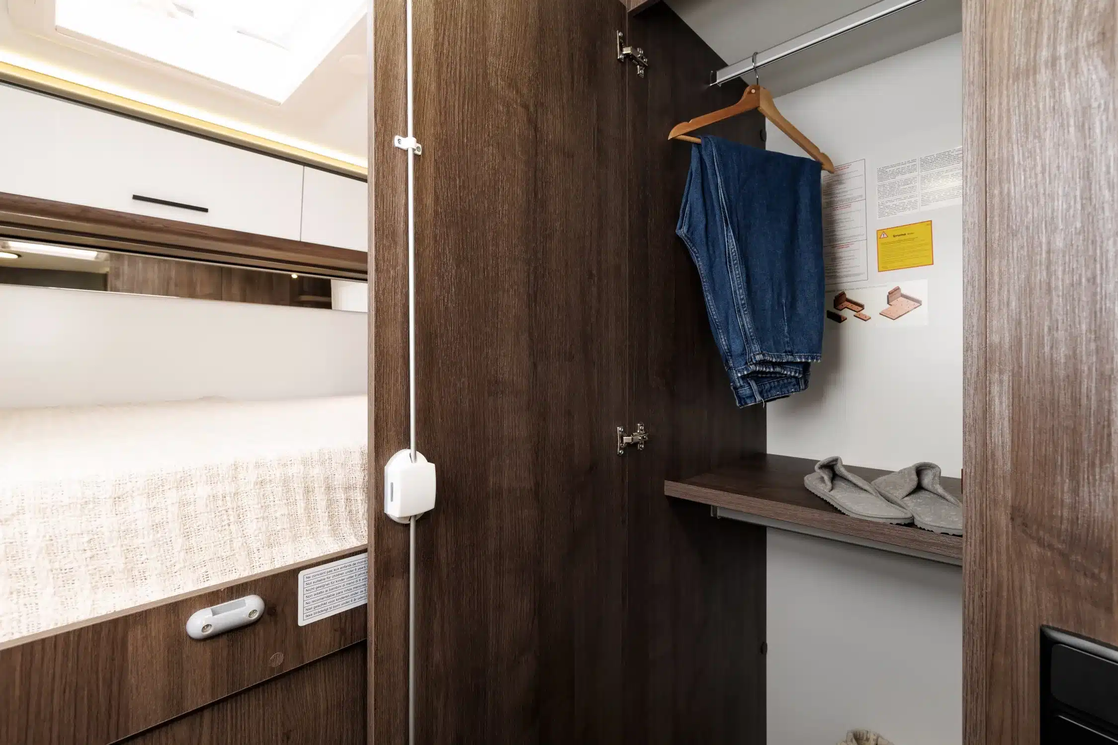 Offener Kleiderschrank mit Jeanshose und Hausschuhen im Benimar Tessoro T444 Reisemobil.